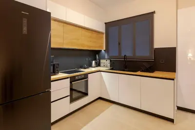 a kitchen with white cabinets and a black refrigerator at Phaedrus Living Athens Metsovou Residence in Athens