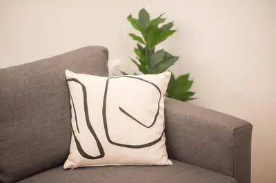 a pillow on a couch with a plant in the background at New Central Apt in Kolonaki in Athens