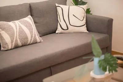 a gray couch with a pillow and a table at New Central Apt in Kolonaki in Athens