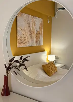a bedroom with a circular mirror above a bed at ArtemisAth in Athens