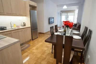 a kitchen and dining room with a table with red flowers at Charming Apt Near Athens Museum! in Athens
