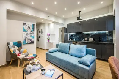 a living room with a blue couch and a kitchen at Elegant, Spacious and hitech apt at Koukaki in Athens