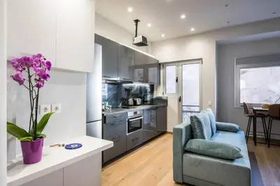 a kitchen and living room with a couch and a vase of flowers at Elegant, Spacious and hitech apt at Koukaki in Athens