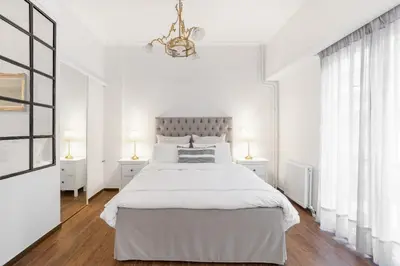a white bedroom with a large bed and two lamps at Unique apartment next to Acropolis and metro in Athens