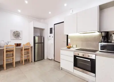 a kitchen with white cabinets and a stainless steel refrigerator at Stunning apartment next to Acropolis and metro in Athens