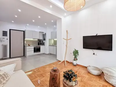 a living room with a couch and a tv on a wall at Stunning apartment next to Acropolis and metro in Athens