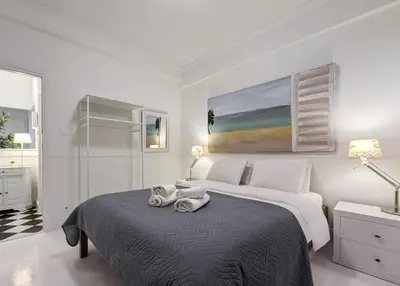 a white bedroom with a bed and a painting on the wall at Chessboard styled 2BD apt next to Acropolis&Metro in Athens