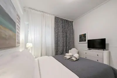 a white bedroom with a bed and a flat screen tv at Chessboard styled 2BD apt next to Acropolis&Metro in Athens