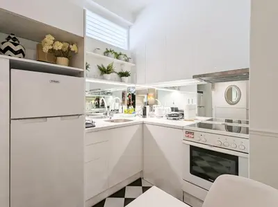 a white kitchen with white cabinets and appliances at Chessboard styled 2BD apt next to Acropolis&Metro in Athens