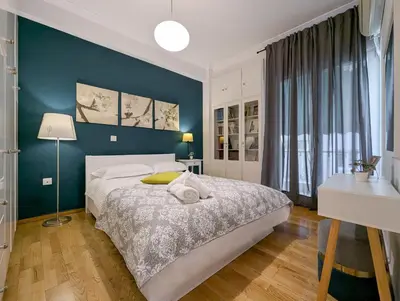 a bedroom with a large bed and a blue wall at Spacious apt for 5 guests next to Acropolis&metro in Athens