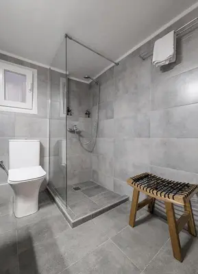 a bathroom with a shower and a toilet and a bench at Spacious apt for 5 guests next to Acropolis&metro in Athens
