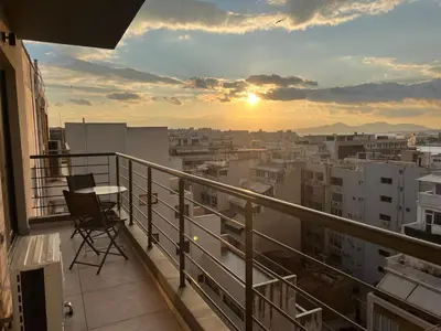 a balcony with a view of a city at sunset at Kolokotroni Apartment in Piraeus
