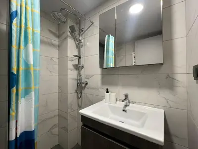 a white bathroom with a sink and a shower at Kolokotroni Apartment in Piraeus