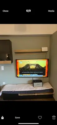 a flat screen tv on a wall above a bed at Ourania26! in Glyka Nera