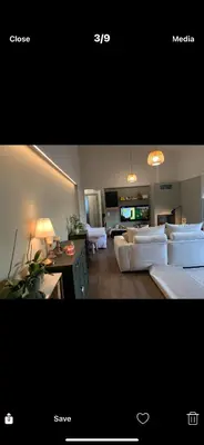 a living room with white couches and a tv at Ourania26! in Glyka Nera