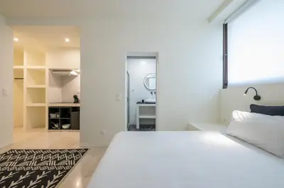 a bedroom with a large white bed and a bathroom at Syrou 1834 in Athens