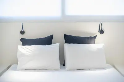 two pillows on a white bed with a window at Syrou 1834 in Athens