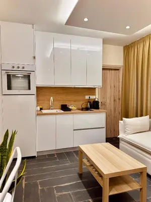 a kitchen with white cabinets and a table and a couch at Ermou 18 Central Cozy Apartment in Athens