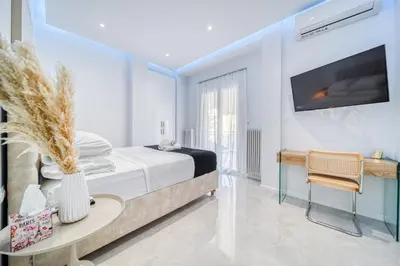 a white bedroom with a bed and a table at Infinity penthouse in Koukaki in Athens