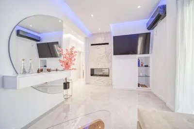 a white living room with a mirror and a fireplace at Infinity penthouse in Koukaki in Athens