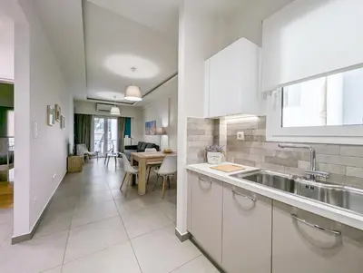 a kitchen with white cabinets and a sink and a table at Modern&Stylish 1BD apt next metro and Acropolis in Athens