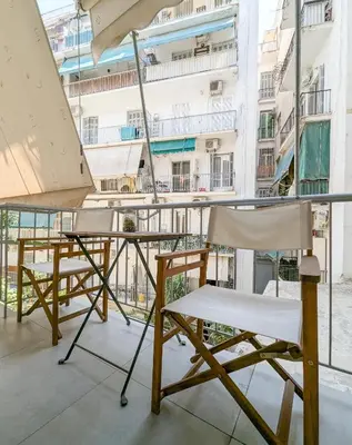 a pair of chairs and an umbrella on a balcony at Modern&Stylish 1BD apt next metro and Acropolis in Athens