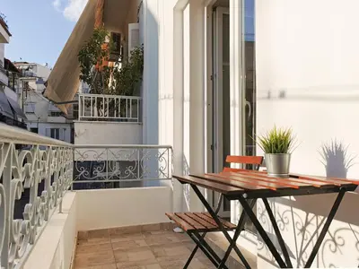 a balcony with a wooden table and chairs on a building at Contemporary 2BD apt with terrace Historic center in Athens