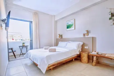 a white bedroom with a bed and a balcony at M&H and their friends 2 in Athens
