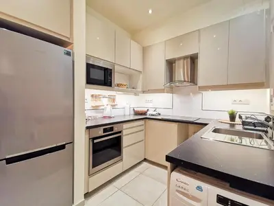 a kitchen with white cabinets and a black counter top at Modern&Sunny, 1BD, next to metro in Athens