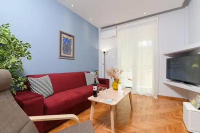a living room with a red couch and a table at Iconic 2BD apt next to Historic center and metro in Athens