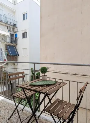 a wooden table and chairs on a balcony at Greek island styled 1BD apt 500m from the sea in Athens