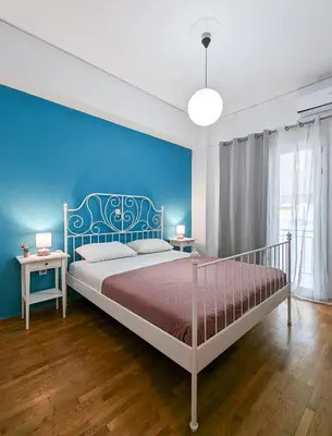 a bedroom with a bed and a blue wall at Cozy 1BD apt next to Kallimarmaro Stadium in Athens