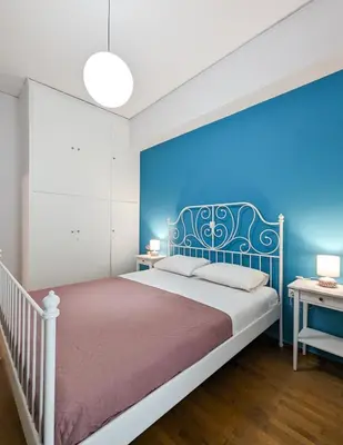 a bedroom with a bed with a blue wall at Cozy 1BD apt next to Kallimarmaro Stadium in Athens