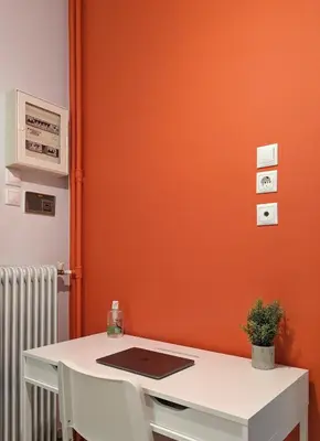 an orange wall with a white desk with a laptop on it at Cozy 1BD apt next to Kallimarmaro Stadium in Athens