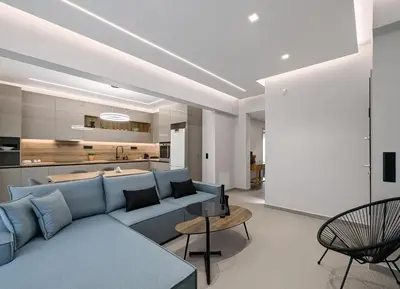 a living room with a blue couch and a kitchen at Acropolis view 3BD penthouse next to tram and port in Piraeus