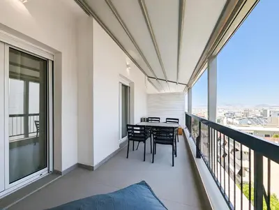 a balcony with a table and chairs on it at Acropolis view 3BD penthouse next to tram and port in Piraeus