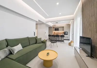 a living room with a green couch and a table at Acropolis view 2BD penthouse next to tram and port in Piraeus