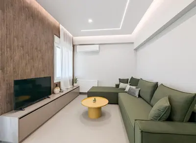 a living room with a green couch and a tv at Acropolis view 2BD penthouse next to tram and port in Piraeus