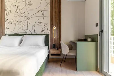 a bedroom with a bed and a desk with a drawing on the wall at Phalerus Suites in Athens
