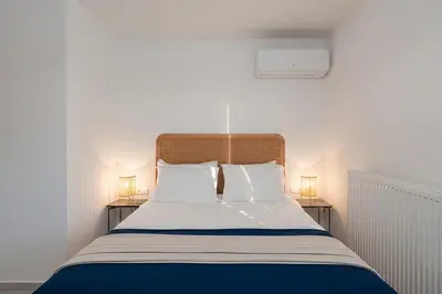 a bed with two white pillows and two lamps at Lofos Lumina Suites in Athens