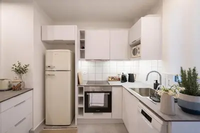 a kitchen with white cabinets and a refrigerator at Lofos Lumina Suites in Athens