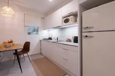 a kitchen with white cabinets and a wooden table at Lofos Lumina Suites in Athens