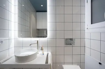 a white bathroom with a sink and a mirror at Lofos Lumina Suites in Athens