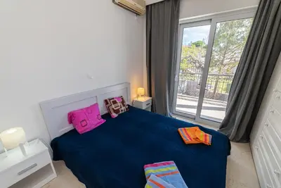 a bedroom with a blue bed and a large window at Chris Guesthouses in Anavissos