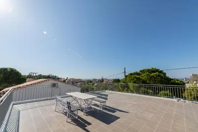 a patio with a table and benches on a balcony at Chris Guesthouses in Anavissos