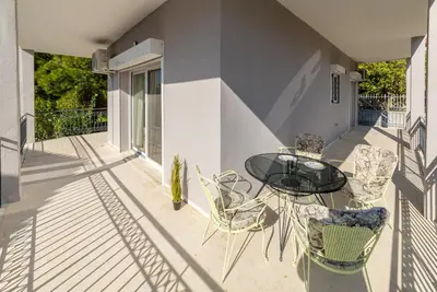 a balcony with a glass table and chairs at Chris Guesthouses in Anavissos