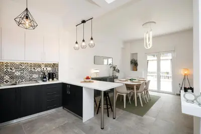 a kitchen with a white counter and a dining room at Acropolis Sights - Greecing in Athens
