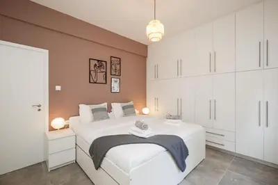 a bedroom with a large white bed and white cabinets at Acropolis Sights - Greecing in Athens