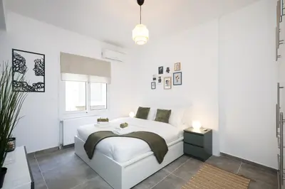 a white bedroom with a white bed and a window at Acropolis Sights - Greecing in Athens
