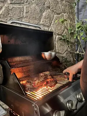 a person is cooking food on a grill at Modern Bohemian Suites ATHENS -- AVM in Athens